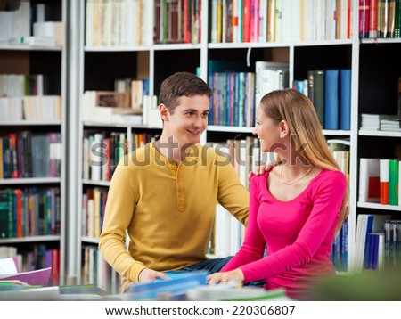 Couple of smiling young readers in a library