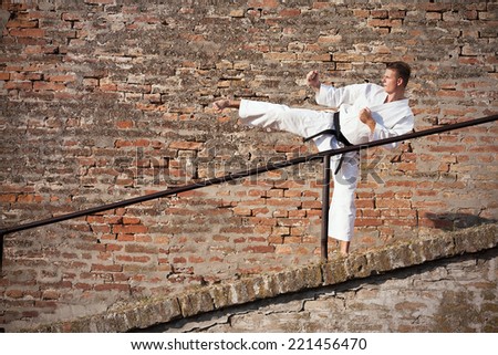Young man practicing martial arts in front of a brick wall.
