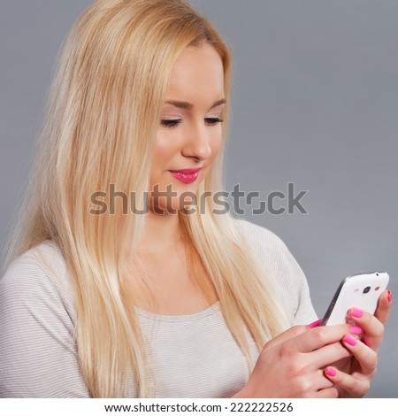 Portrait of a beautiful young woman texting with her phone. Studio shot.