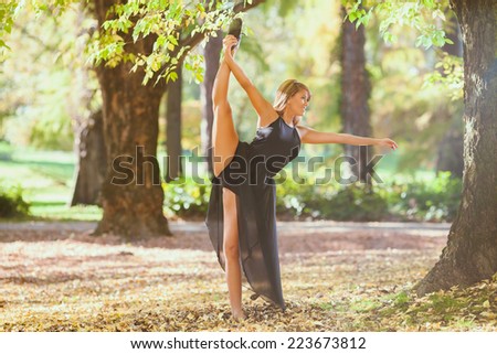 Attractive female dancing in park on beautiful autumn day.