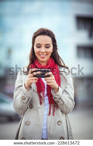Beautiful young woman on the street text messaging.