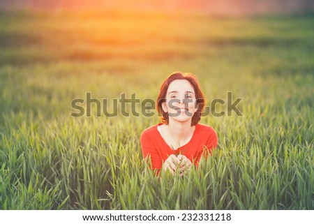 Beautiful young woman enjoying nature in a green field on sunset or sunrise