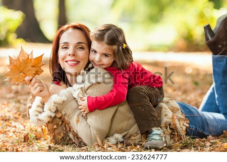 Beautiful mother and little daughter enjoying nice autumn day in a park