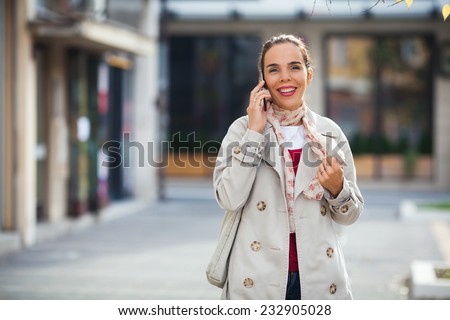 Smiling young woman on the street talking on the phone