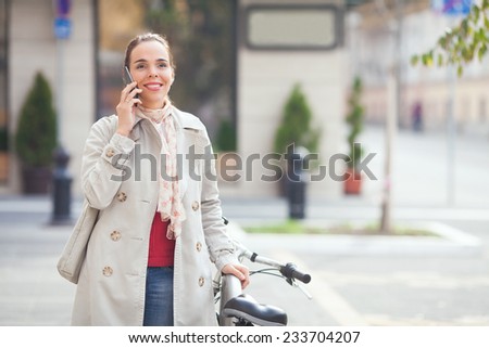 Young woman on the phone next to bicycle on the street