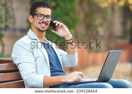 Businessman working on a laptop sitting on a park bench