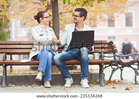 Two people shaking hands while sitting on a park bench
