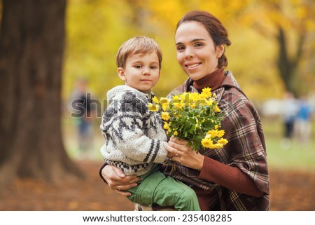 Mother carrying her son in one hand and flowers in the other hand