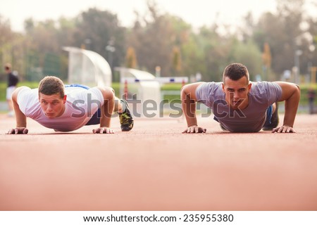 Two young athletes doing push-ups outdoors.
