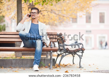 Young man sitting on the park bench talking on the mobile phone
