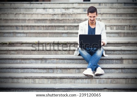 Young man sitting on the stairs using laptop