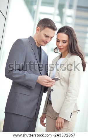 Two young business people looking at mobile phone
