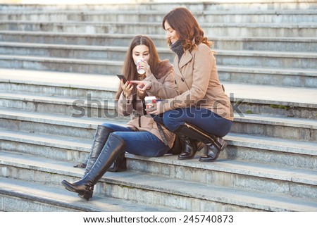 Two young friends drinking coffee and chatting in front of the office building