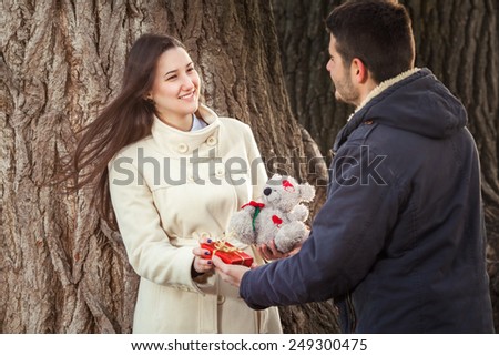 Young couple exchanging presents for Valentine\'s Day in nature