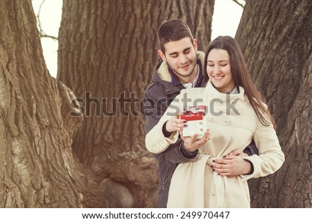 Romantic young couple opening gifts in nature