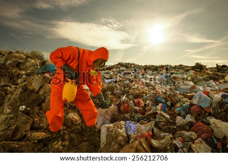 Sanitation worker processing  waste material (sorting, treatment, recycling) on the landfill.