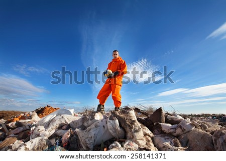 Sanitation worker standing among garbage bags holding a volleyball ball.