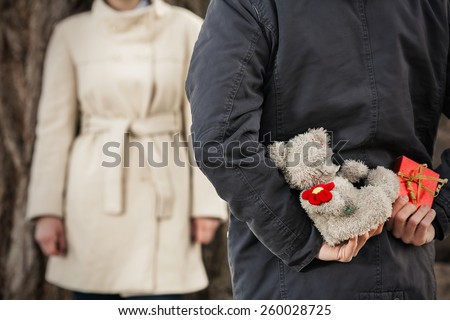Close-up of gifts young man holding behind his back to surprise his girlfriend