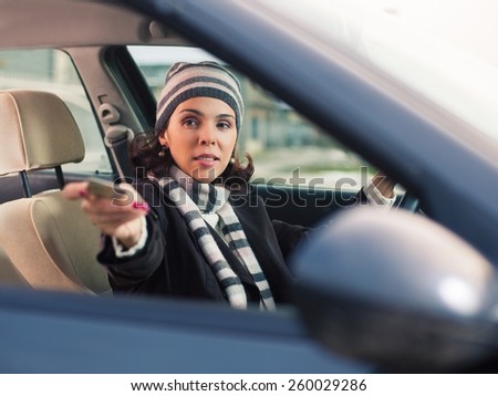 Young woman sitting in a car showing her drivers license.