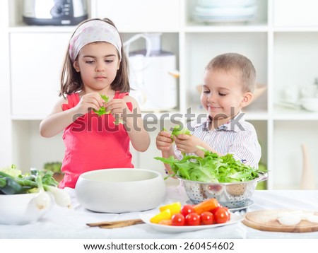 Two cute little children making salad in the kitchen