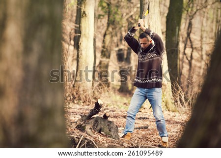 Young lumberman cutting the tree with an axe
