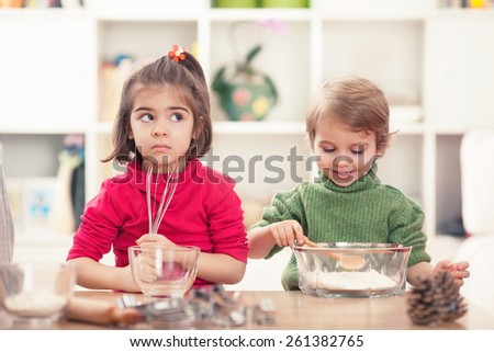 Cute little girl and boy learning how to bake cookies