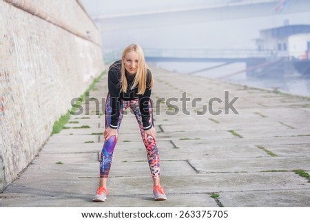 Attractive female jogger taking a rest after a run by the river