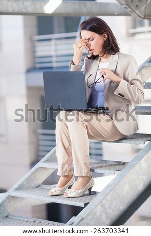 Young businesswoman tired of working on laptop