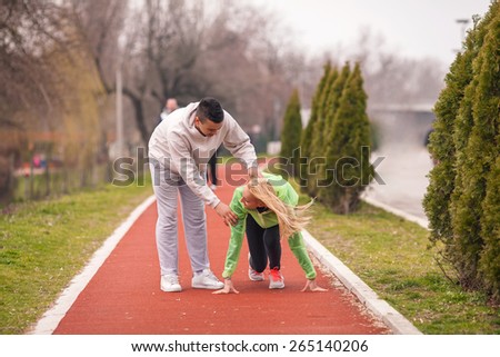 Young female athlete practicing with her coach on running track