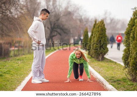 Young female athlete practicing with her coach on running track