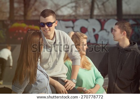 Group of young people hanging out in a schoolyard or park. Portrait of young man with sunglasses