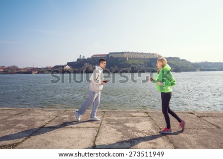 Two young people running in opposite directions by the Danube river in Novi Sad, Serbia