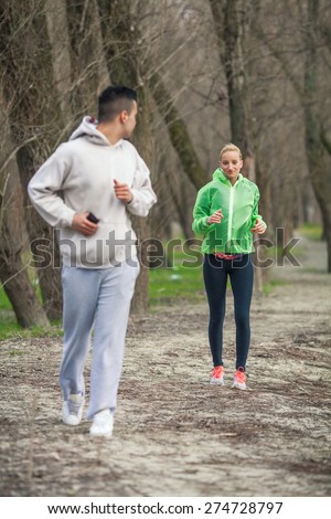 Young man looking up for a girl running behind him in a forest