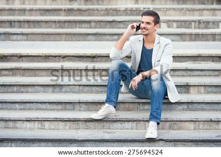 Young man sitting on the stairs talking on the mobile phone