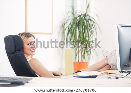 Young businesswoman daydreaming in an office with her foot on the desk
