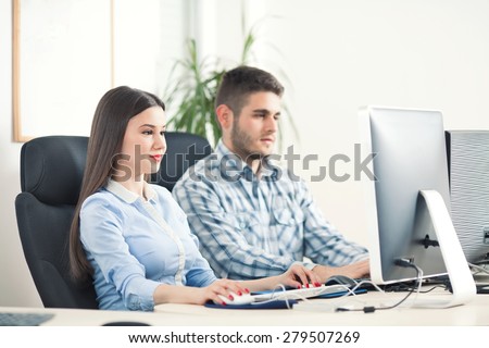 Portrait of young businesspeople typing on computer keyboard and looking at computer monitor