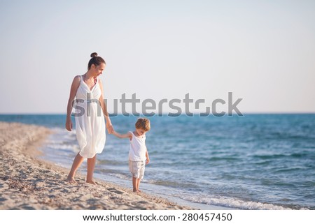 Mother and son walking along beach