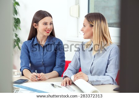 Two young female designers discussing their ideas in an office
