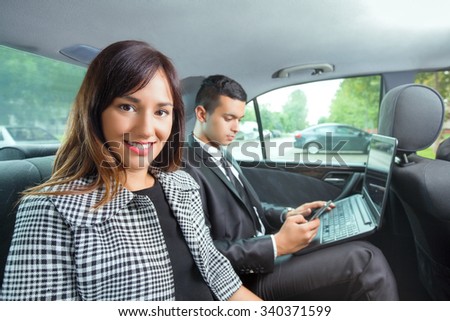 Young business team sitting on the backseat of a taxi while traveling to work