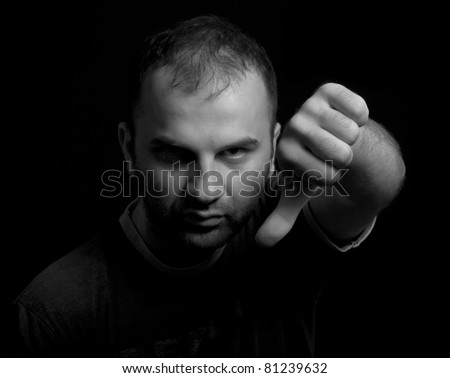 Closeup of young man pointing finger down and expressing dislike. Black and white portrait