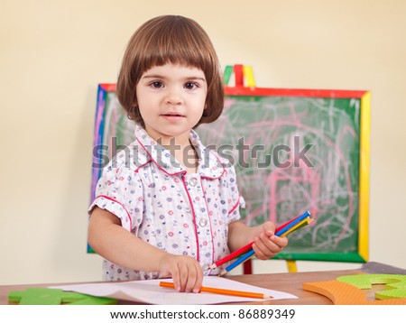 Adorable little smiling toddler girl drawing portrait