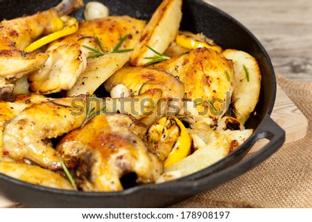 Garlic, Lemon and Rosemary Roasted Chicken on Frying Pan with potato. Selective focus.