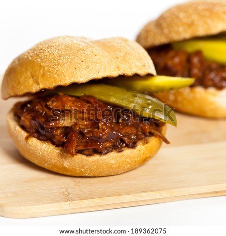 Pulled pork sandwich on a bun with two pickles. Selective focus.