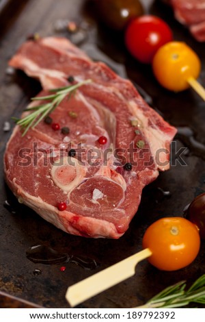 Raw lamb chops with cherry tomato and rosemary herb ready to cook. Selective focus.