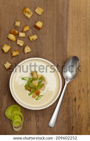 A bowl of Leek and Potato soup with croutons, over old wood table