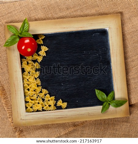 Italian Food. Pasta, Tomatoes, Basil on black chalkboard. Selective focus.