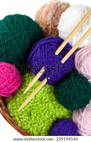 Balls of yarn in a basket with knitting needles isolated on white. Selective focus.