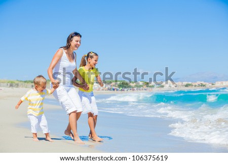 Happy family of three - mother and her child running and having fun on tropical beach