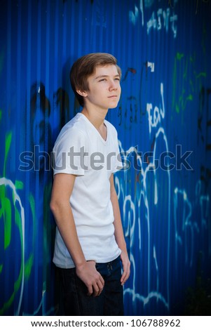Young smile teenager in front of blue graffiti