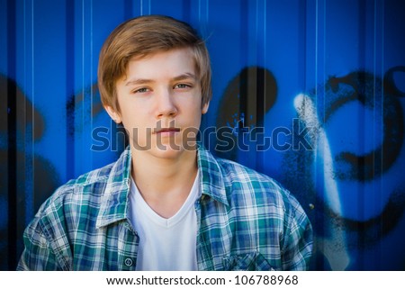 Portrait of young smile teenager in front of blue graffiti